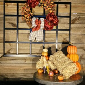 A wooden wall with a wreath and some pumpkins