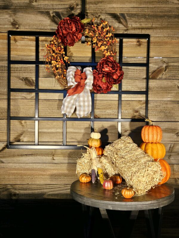 A wooden wall with a wreath and some pumpkins