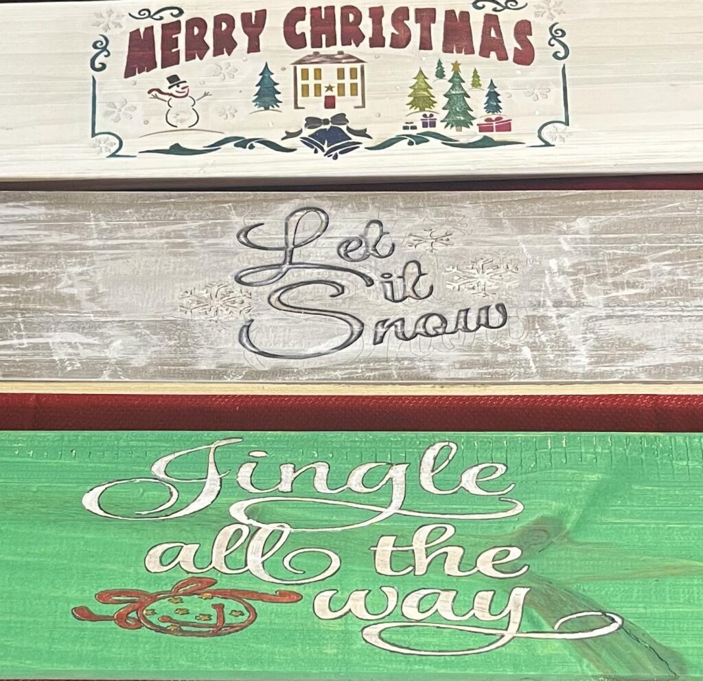 A trio of christmas signs with different designs.