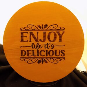 A wooden plaque with the words " enjoy life its delicious ".