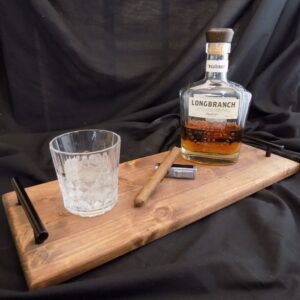 A bottle of whiskey and a glass on a wooden board.