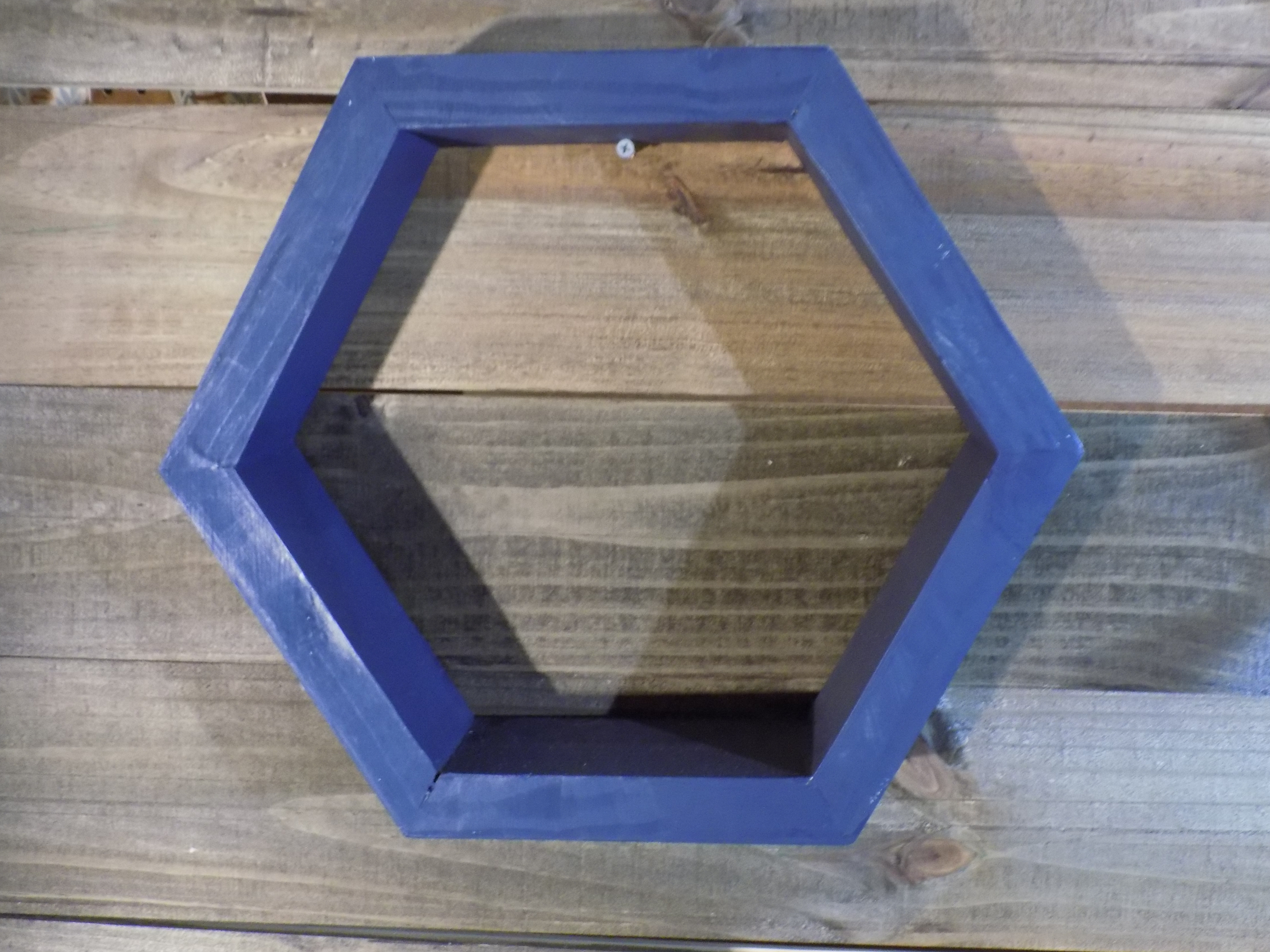 A blue hexagonal shelf on top of a wooden table.