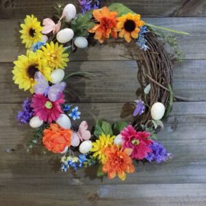 A wreath of flowers and eggs on top of a wooden table.