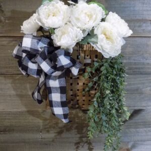 A basket with flowers and greenery hanging on the wall.